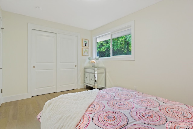 bedroom with light wood-type flooring, baseboards, and a closet