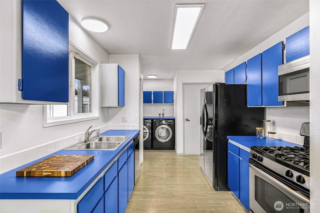 kitchen with black appliances, blue cabinetry, a sink, and washing machine and clothes dryer