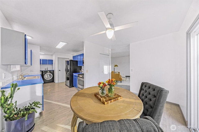 dining area featuring washer / dryer, light wood-style flooring, and a ceiling fan