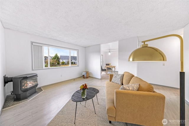 living area featuring a wood stove, a textured ceiling, and wood finished floors