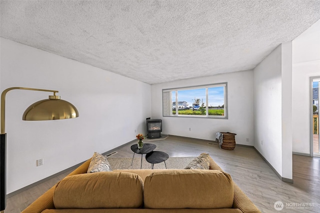 living room featuring a textured ceiling, wood finished floors, visible vents, baseboards, and a wood stove