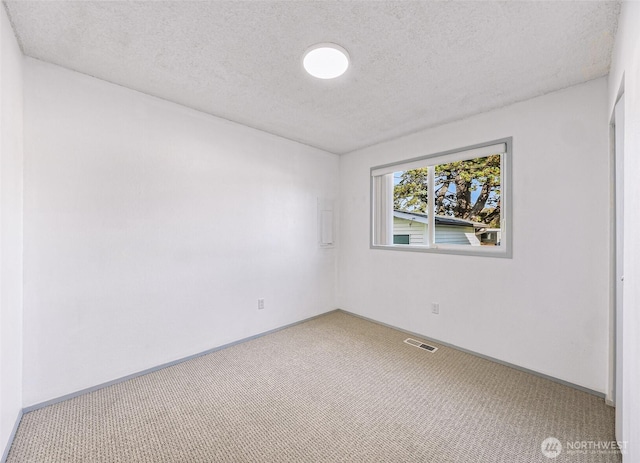 unfurnished room with baseboards, carpet, visible vents, and a textured ceiling