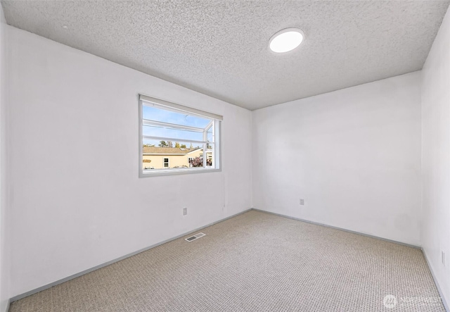 carpeted spare room featuring visible vents, a textured ceiling, and baseboards