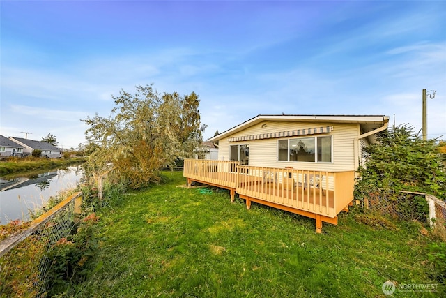 back of house with a deck with water view and a yard