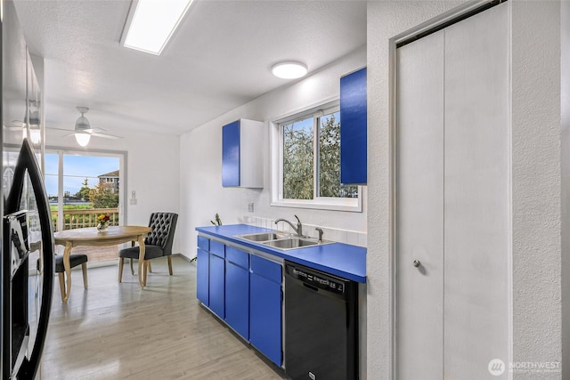 kitchen featuring a sink, refrigerator with ice dispenser, light wood-style floors, black dishwasher, and blue cabinetry