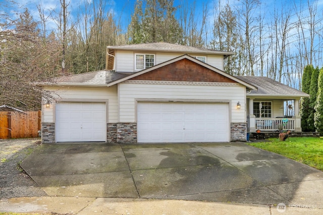 view of front of home featuring a garage, stone siding, driveway, and a porch