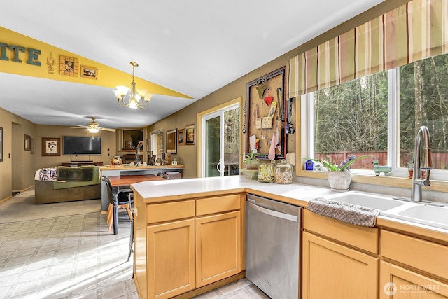 kitchen featuring light countertops, open floor plan, a sink, dishwasher, and a peninsula