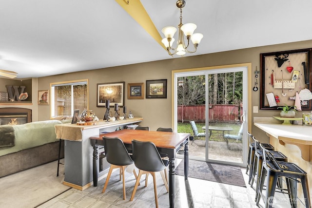 dining space featuring a warm lit fireplace and a chandelier