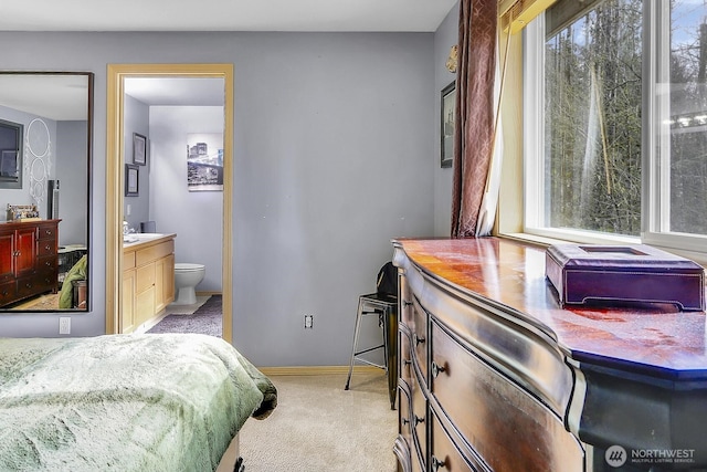 bedroom with light carpet, connected bathroom, a sink, and baseboards