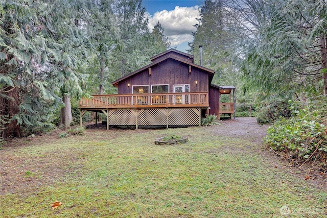 rear view of house with a forest view, a lawn, and a wooden deck