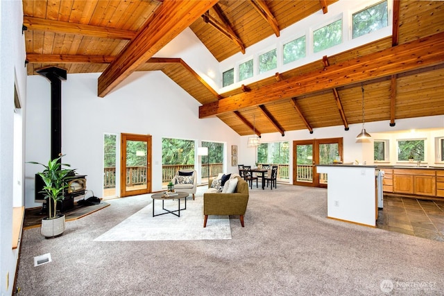 living area featuring visible vents, wooden ceiling, a wood stove, high vaulted ceiling, and dark carpet