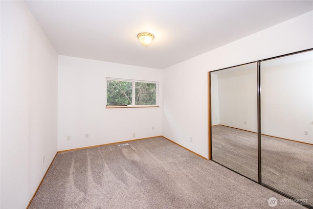 unfurnished bedroom featuring carpet, a closet, and baseboards