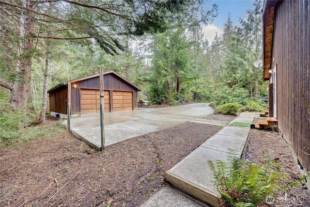 view of yard featuring a detached garage, a wooded view, and an outbuilding