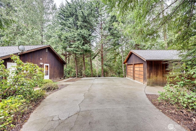 view of side of home featuring a garage, a shingled roof, and an outdoor structure