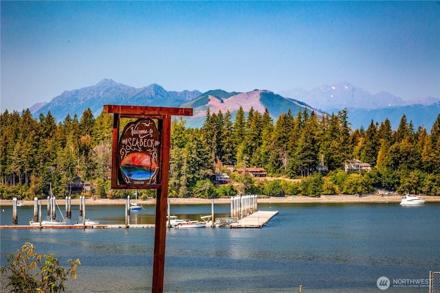 exterior space featuring a boat dock, a wooded view, and a water and mountain view