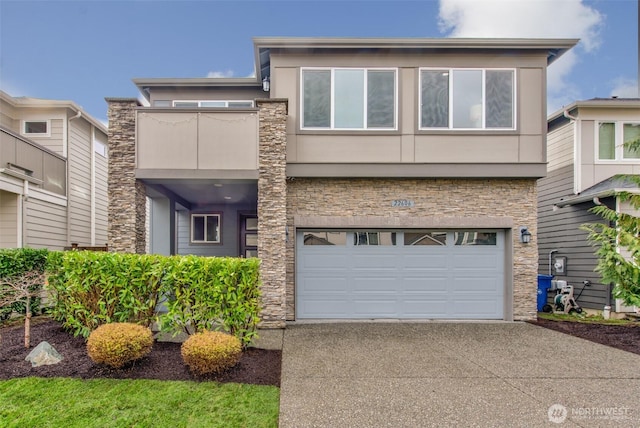 view of front of house with concrete driveway, stone siding, an attached garage, and stucco siding