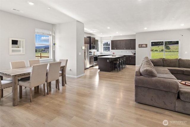 living area with baseboards, light wood finished floors, visible vents, and recessed lighting