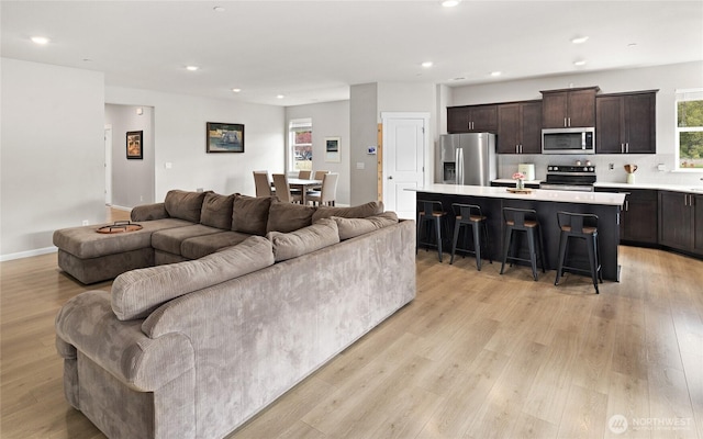 living area featuring baseboards, recessed lighting, and light wood-style floors