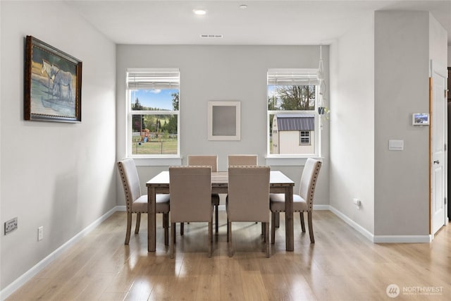 dining space with baseboards, visible vents, and light wood-style floors