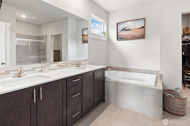 bathroom featuring a stall shower, tile patterned flooring, a sink, and a garden tub