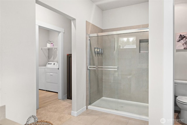 bathroom featuring washer / dryer, a shower stall, toilet, and tile patterned floors