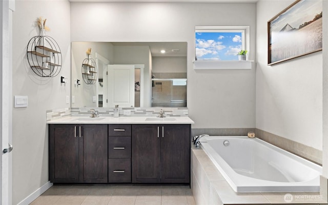 bathroom with a garden tub, double vanity, a stall shower, and a sink