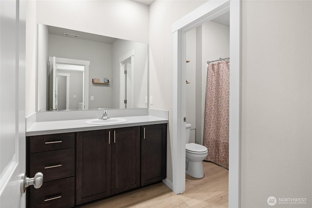 bathroom featuring toilet, wood finished floors, vanity, visible vents, and a shower with curtain