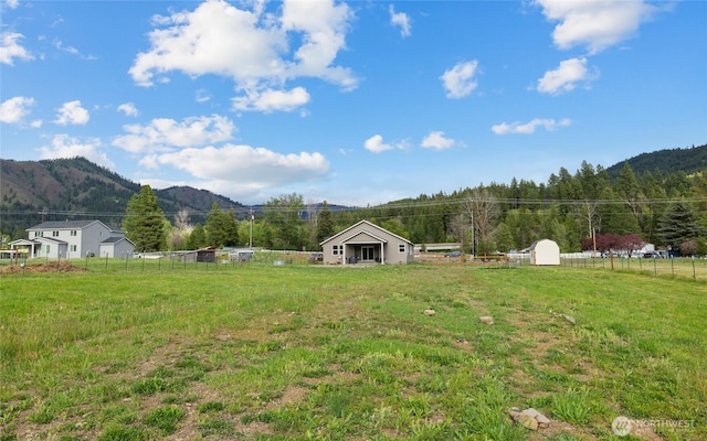 view of yard featuring a rural view, fence, and a mountain view