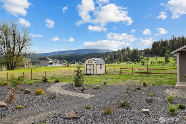 view of yard with fence, a storage unit, an outdoor structure, and a rural view