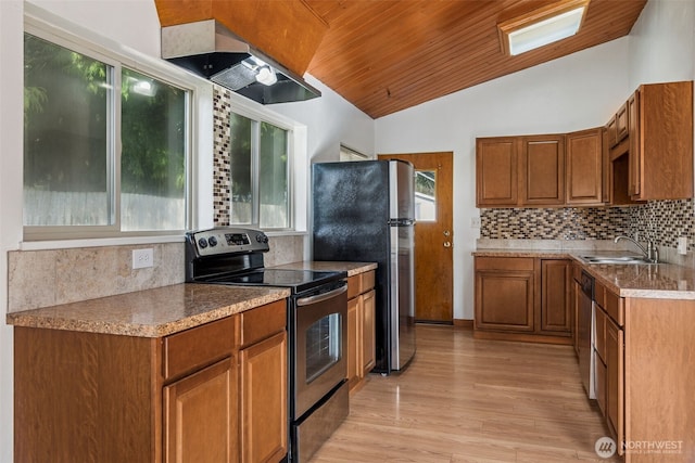 kitchen with brown cabinetry, lofted ceiling, appliances with stainless steel finishes, range hood, and backsplash