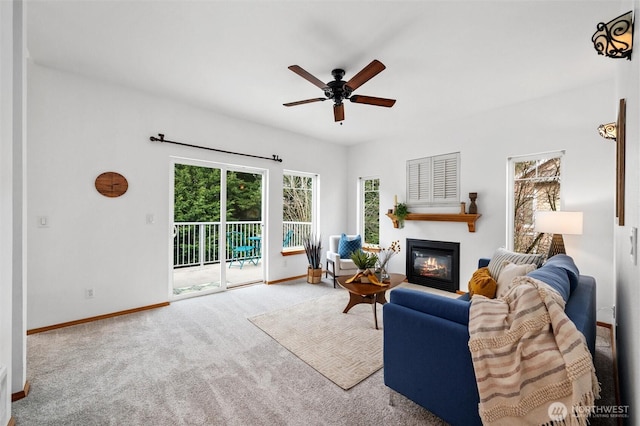 carpeted living room with a glass covered fireplace, a ceiling fan, and baseboards