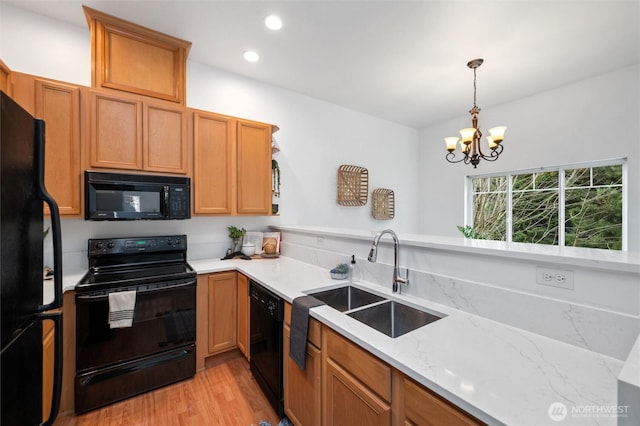 kitchen featuring a sink, light wood-style floors, light stone countertops, black appliances, and an inviting chandelier