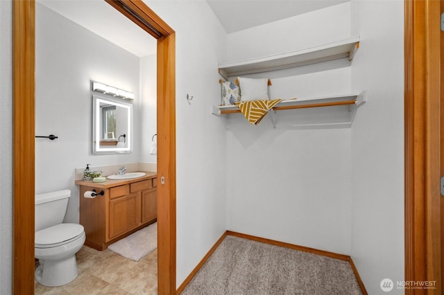 half bathroom featuring vanity, toilet, and baseboards