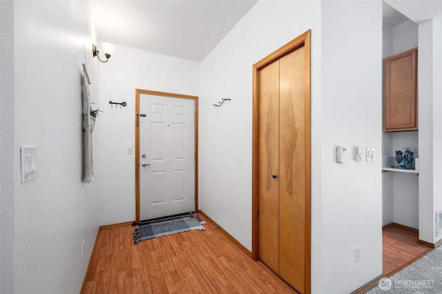 doorway with baseboards, visible vents, and light wood-style floors