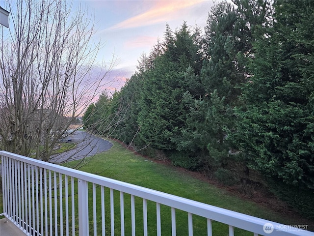 yard at dusk featuring a balcony