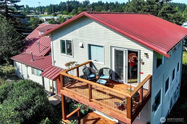 back of house featuring metal roof, a wooden deck, and a standing seam roof