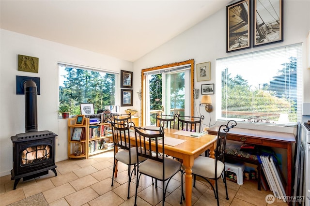 dining space with vaulted ceiling and a wood stove