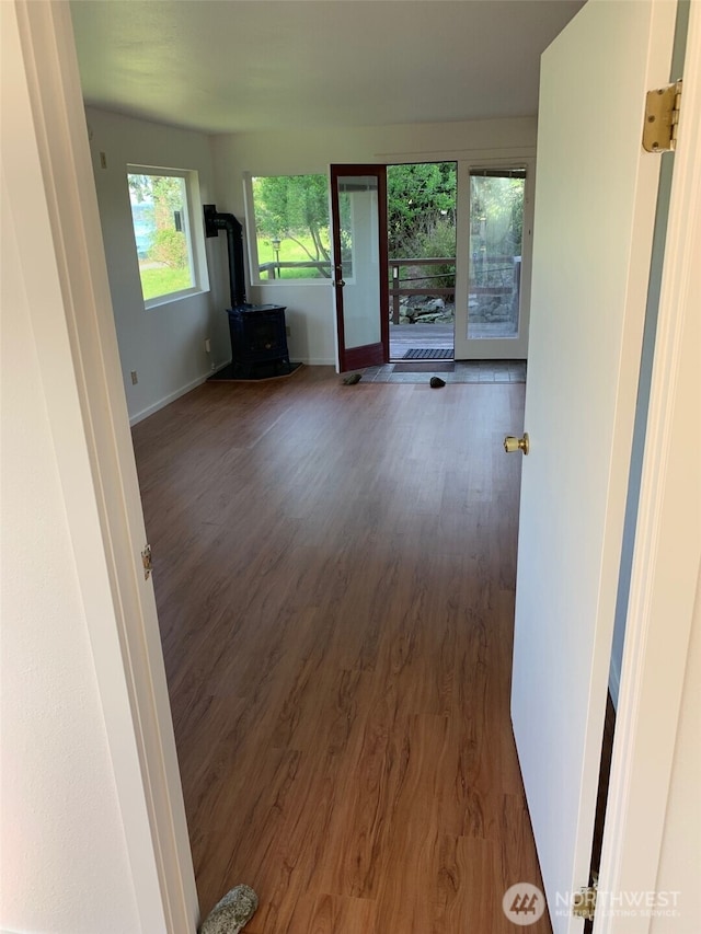 interior space with a wood stove, wood finished floors, and baseboards