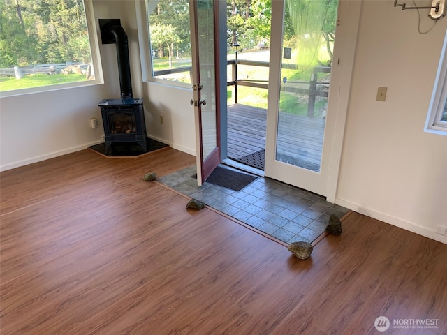 entryway featuring baseboards, wood finished floors, and a wood stove