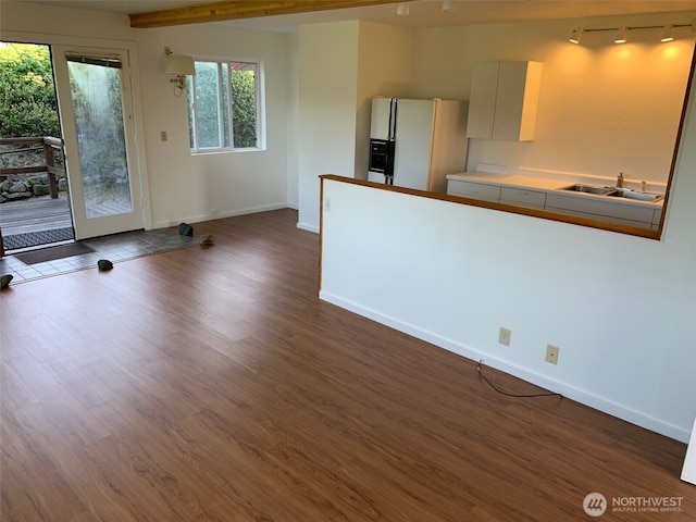 kitchen with dark wood-style floors, a sink, baseboards, and white fridge with ice dispenser