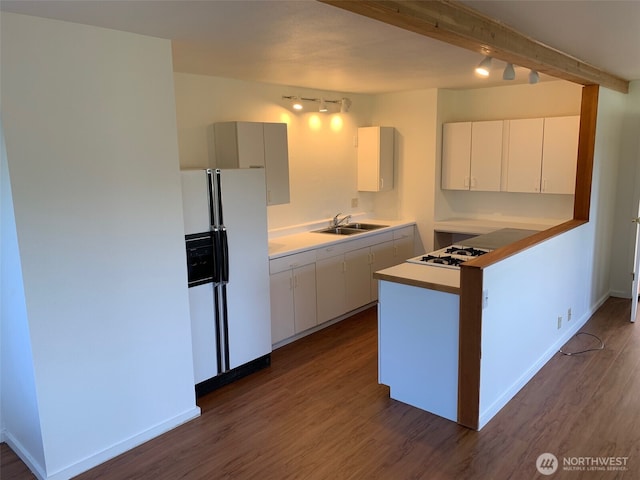 kitchen with a peninsula, white refrigerator with ice dispenser, dark wood-style flooring, and a sink