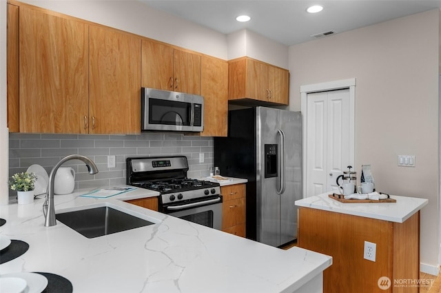 kitchen with visible vents, appliances with stainless steel finishes, brown cabinetry, and a sink