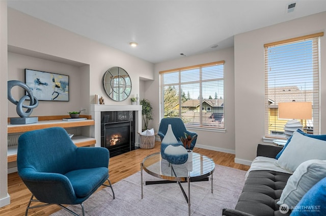 living area with a tile fireplace, recessed lighting, baseboards, and wood finished floors