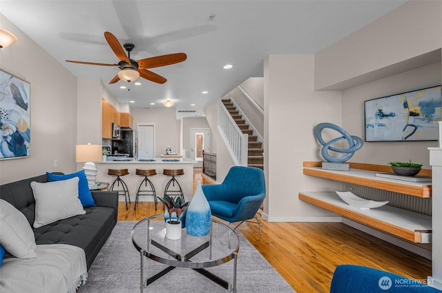 living room featuring light wood-style floors, baseboards, stairway, and recessed lighting