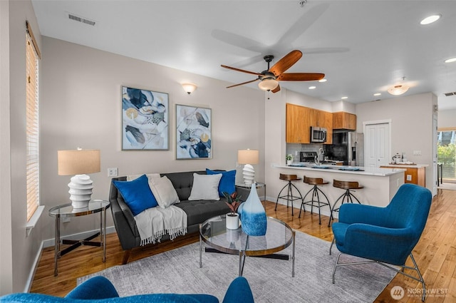 living room featuring recessed lighting, visible vents, ceiling fan, light wood-type flooring, and baseboards