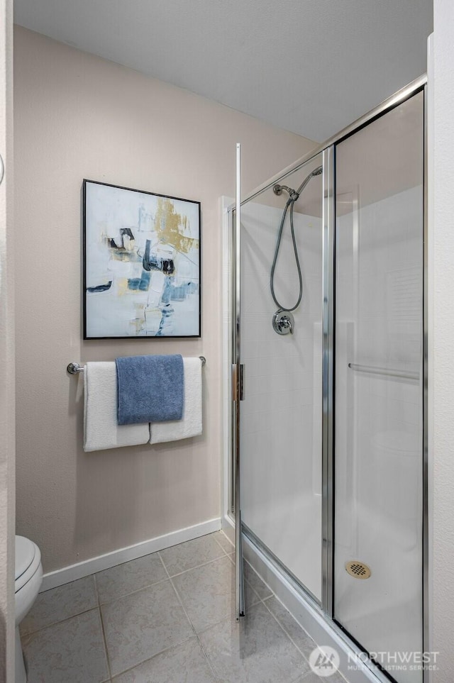 bathroom featuring baseboards, a shower stall, toilet, and tile patterned floors