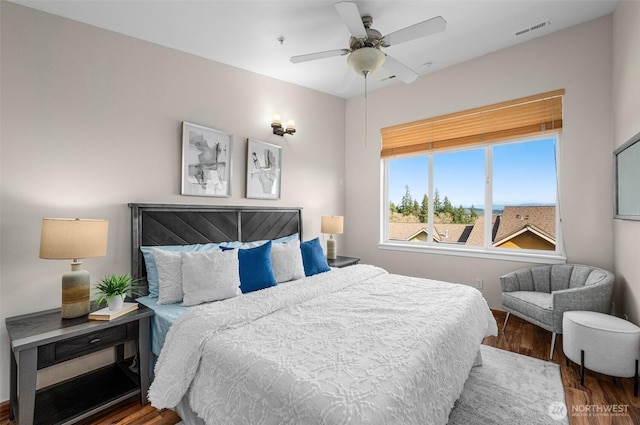 bedroom with a ceiling fan, visible vents, and wood finished floors