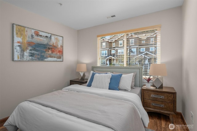 bedroom featuring baseboards, visible vents, and wood finished floors