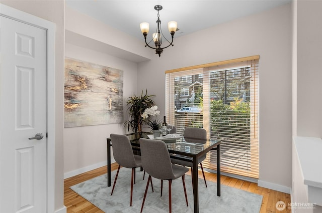 dining space featuring a chandelier, light wood-style flooring, and baseboards