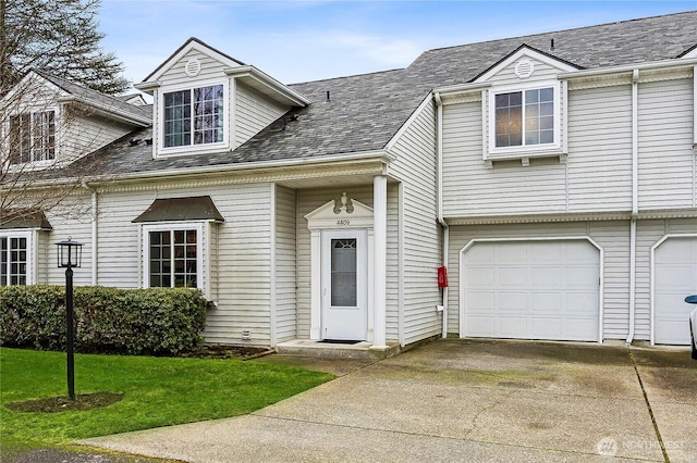 view of front of property featuring a garage, driveway, a shingled roof, and a front yard